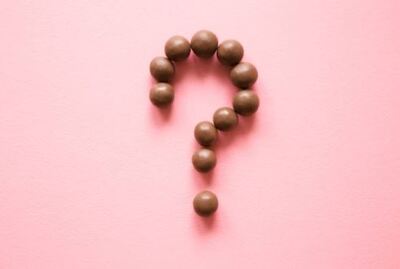 chocolate candies arranged in a question mark on pink background
