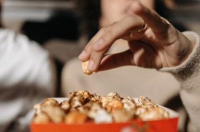 woman mindlessly reaching for caramel popcorn wondering why am i eating so much