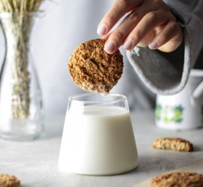 woman dunking a cookie into a glass of milk to actually stop hedonic eating